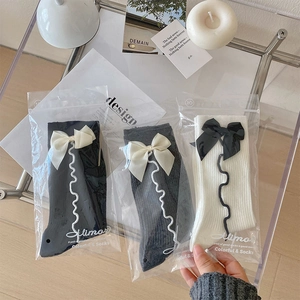 Tre paia di calzini a metà polpaccio in nero, grigio e bianco con fiocchi in buste