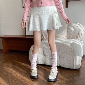 Detail showing white faux fur A-line skirt with decorative plush ball drawstring ties