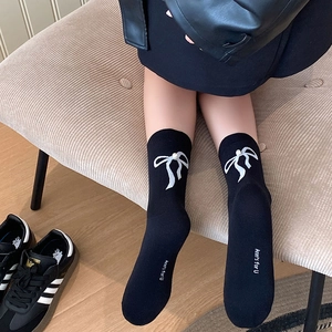 Gros plan détaillé de chaussettes noires style ballet avec nœud perlé et logo imprimé
