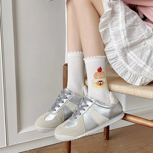 Close-up of white crew socks with colorful cake print and ruffled edges with vintage sneakers