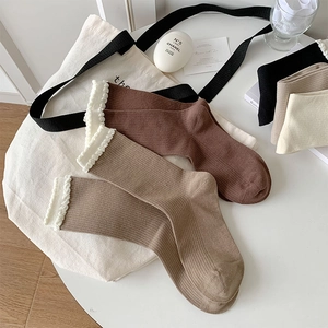 Detailed view of ribbed cotton socks with elegant white lace trim in earthy tones