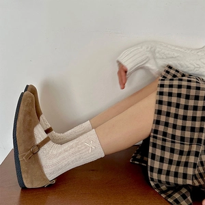 Detail of white cable knit crew socks featuring cross-stitch embroidery with Mary Janes