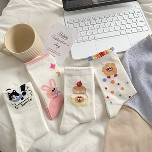 Detailed view of four pairs of white cotton socks featuring cute cartoon animal prints
