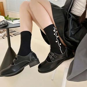 Detail of black rib socks with pearl beads and wave trim worn with Mary Jane shoes