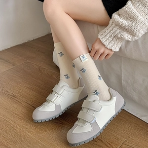 Dettaglio calzini con ricamo di ciliegie blu abbinati a scarpe da ginnastica con velcro