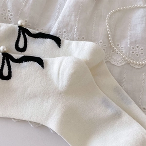 Gros plan de chaussettes blanches en coton avec nœuds noirs et perles douces