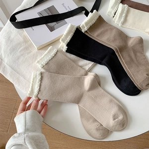 Close-up of ribbed cotton socks with white lace trim in various earthy neutral colors
