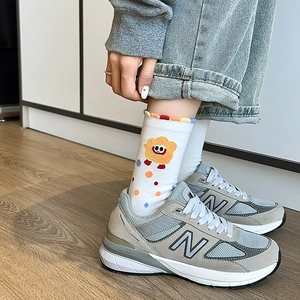 Detail of white cotton sock with rainbow wavy cuff paired with grey sneakers