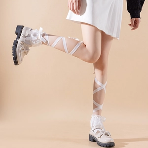 Close-up of off-white platform Mary Janes with lace socks and ribbon leg straps