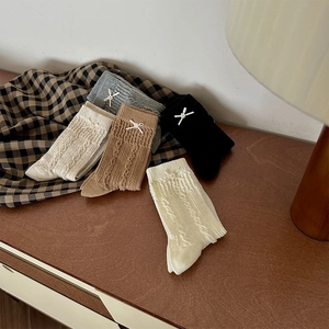 Detail of five-color cable knit socks with cute bow accents on a wooden surface