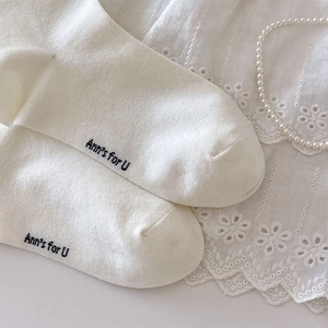 Vue détaillée de chaussettes en coton blanc avec texte noir et accents de perles élégants