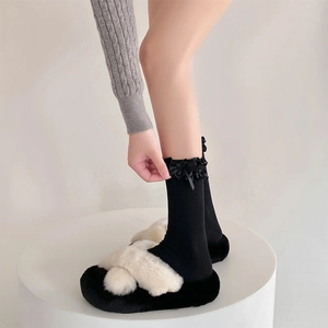 Dettaglio di calze Lolita con pizzo nero e fiocco abbinate a pantofole di peluche