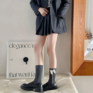 Dettaglio di calze grigio scuro con fiocco e mocassini per uno stile collegiale chic