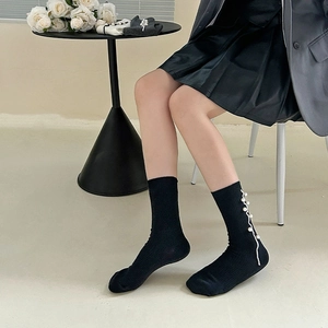 Detailed view of black mid-calf socks with white wavy lines and elegant pearl embellishments