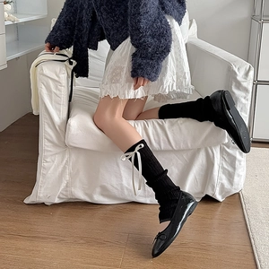Gros plan de jambières en tricot noir avec nœuds en soie blanche et style balletcore