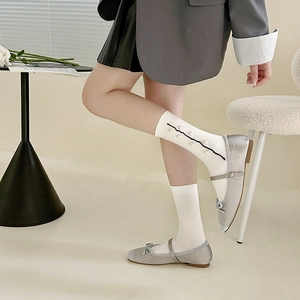 Detail of white ruffle socks with pearl accents and grey satin Mary Jane flat shoes
