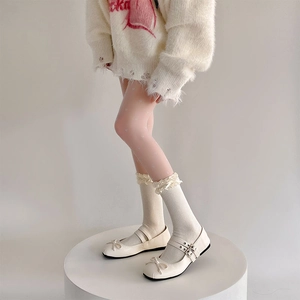 Dettaglio di scarpe Mary Jane bianche con calze a balze e collant con cuori rosa