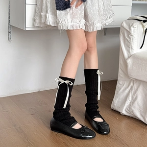 Détail de jambières noires en maille avec nœuds blancs pour un style japonais JK