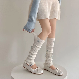 Detailed knit leg warmer featuring light blue satin bows and wavy ruffled edges