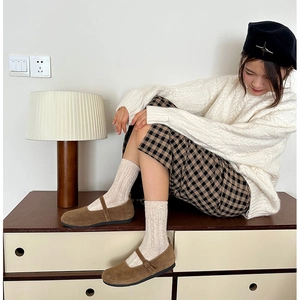 Detail of brown Mary Jane shoes with cream cable knit socks and delicate bow embroidery