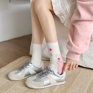 Close-up of white cotton mid-calf socks with pink rabbit patterns and retro sneakers