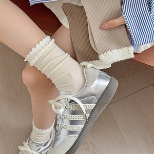 Detail of white ruffle trim ankle socks showing soft cotton knit texture and elastic lace cuff