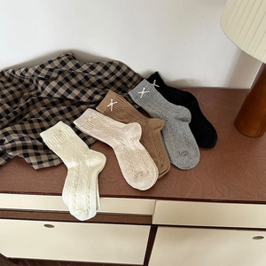 Detail of five-pair knit mid-calf socks with cable patterns and bow accents