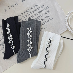 Detail of knit socks with white pearl beads and wavy trim accents in three colors
