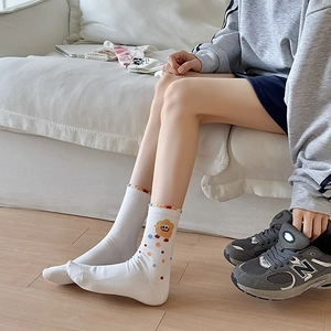 Close-up of white cotton mid-calf socks featuring colorful embroidery and ribbed cuffs