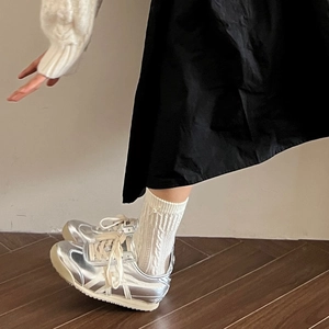 Silver metallic casual sneakers with white stripes paired with white cable knit socks