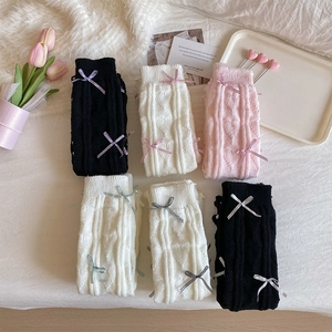 Flat lay of knit leg warmers with ribbon bows in black, white, and pink options