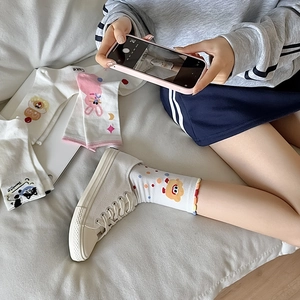 Detail of white cotton crew socks featuring cute cartoon rabbit and bear patterns
