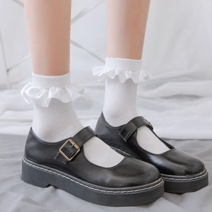 Close-up of black platform Mary Jane shoes with metal buckles and white ruffle socks