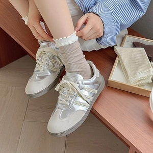 Detailed close-up of silver trainers with suede T-toe design and classic retro gum sole