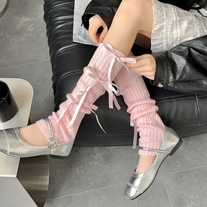 Detail of pink knitted balletcore leg warmers with delicate ribbon bows and ribbed texture