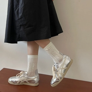 Close-up of metallic silver low-top sneakers with vintage gum soles on a wooden stand