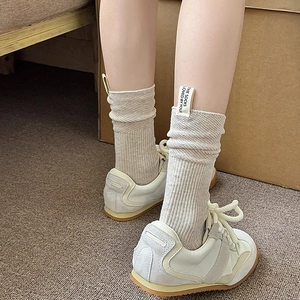 Calze a coste beige con etichetta posteriore indossate con scarpe da ginnastica