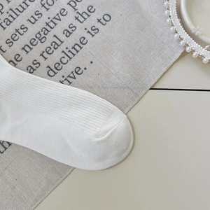 Detailed macro view of white ribbed knit cotton socks with premium texture and stitching