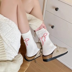 Chaussettes mi-mollet blanches avec nœuds roses et perles dans un décor de style de vie