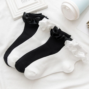 Detail of white and black mesh socks featuring elegant satin bows and lace ruffles