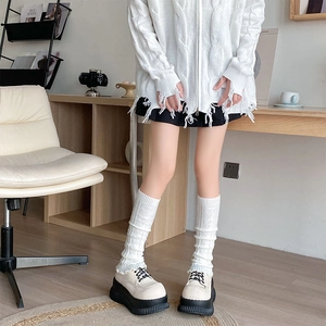 Detail of white cable knit leg warmers paired with platform shoes and oversized hoodie