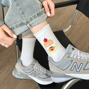 Close-up of white ribbed crew socks with cute cherry embroidery and wavy ruffle cuffs