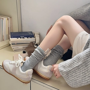 Dettaglio calzini grigi a coste con etichetta tessuta abbinati a sneakers beige rétro
