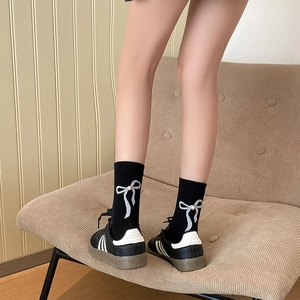 Détail de chaussettes mi-hautes noires avec nœud perlé et texture en coton