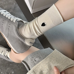 Detail of embroidered heart and ribbed texture on cotton crew socks in cream and grey