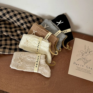Detail of cable knit crew socks with pearl bow accents in various neutral colors