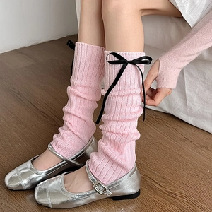 Détail de jambières en tricot rose avec nœuds noirs et texture côtelée douce