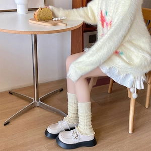 Detailed shot of cream cable knit leg warmers with floral buckle platform Mary Janes