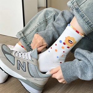 Detail view of white cotton socks with cute bear patterns and scalloped lace cuffs
