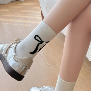 Détail de chaussettes en coton blanc avec nœud noir et perle dans des chaussures argentées